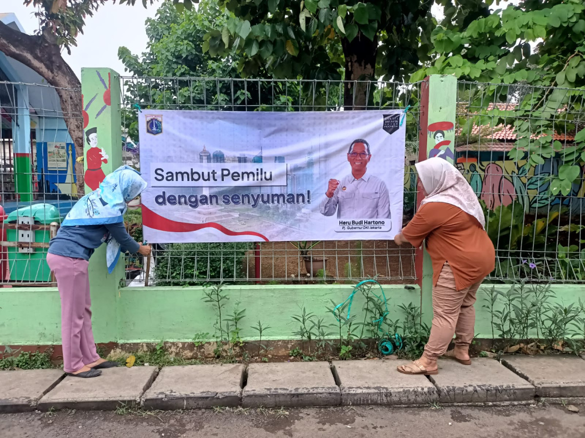 PEMASANGAN SPANDUK SAMBUT PEMILU DENGAN SENYUMAN